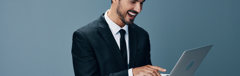 Imagen de un hombre en traje felizmente navegando por internet en su ordenador portátil
