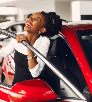 Imagen de una mujer feliz con la compra de su coche de color rojo