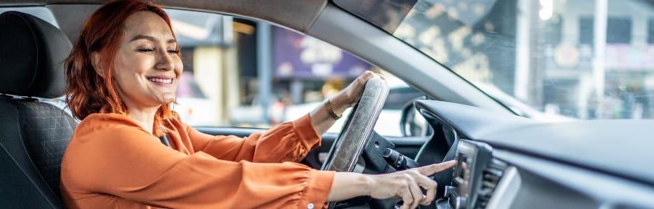 Imagen de una mujer sonriente poniendo la radio en su coche