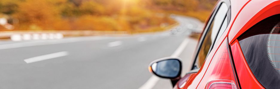 Imagen de un coche de color rojo parado en la acera de una carretera