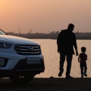 Imagen de un padre con su hijo fuera del coche familiar