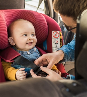 Imagen de un padre poniendo el cinturón de seguridad en el coche de su hijo