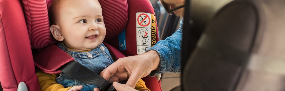 Imagen de un padre poniendo el cinturón de seguridad en el coche de su hijo
