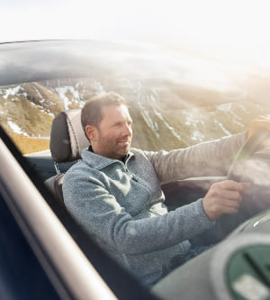 Imagen de un hombre conduciendo un coche por las montañas