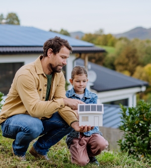 Imagen de un padre enseñando a su hijo un modelo de vivienda sostenible
