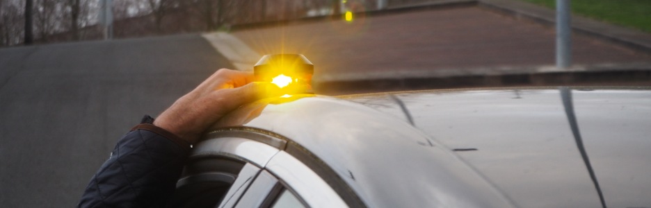 Imagen de una persona colocando una luz de emergencia sobre su coche