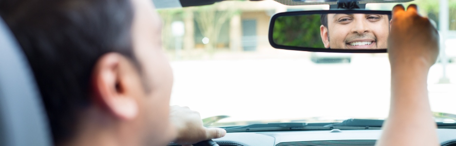 Imagen de una persona en su coche mirándose en el espejo