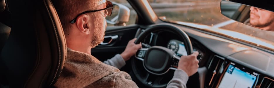 Un hombre con gafas de sol conduciendo un automóvil al atardecer el concepto de viaje en automóvil