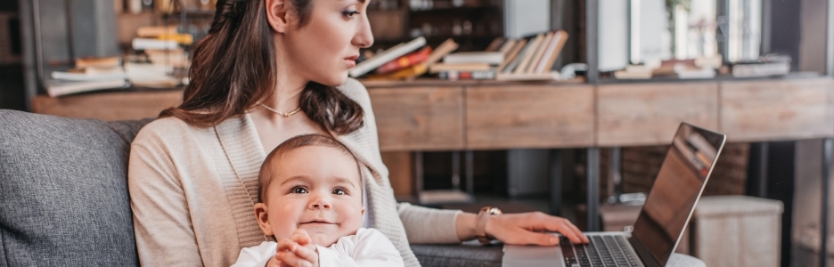 Imagen de madre sentada en el sofá con su hijo y usando la computadora portátil en casa